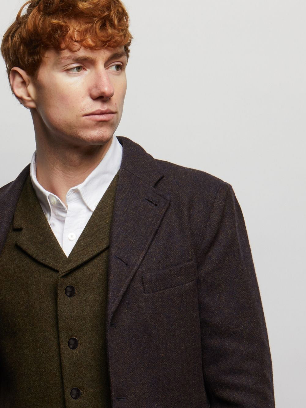 Dark Green Herringbone Sherwood waistcoat under a dark jacket, close-up