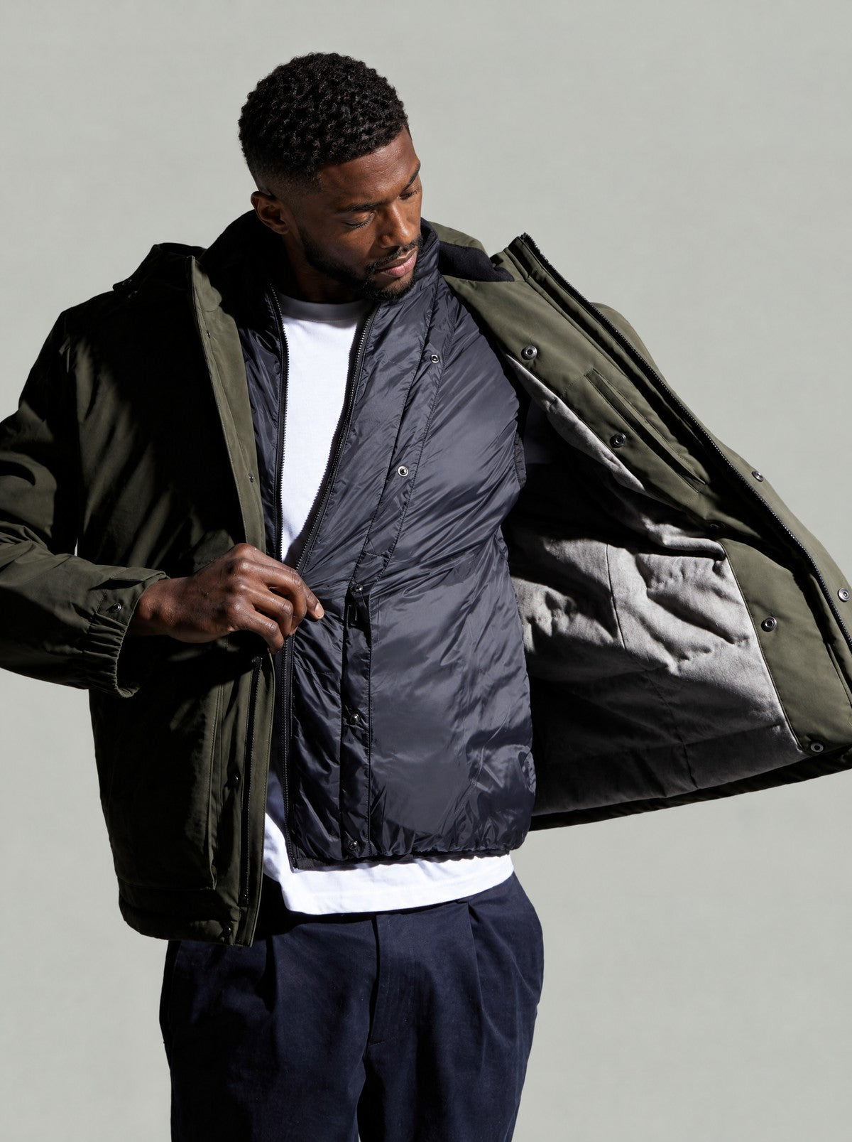 Model opening the Green Leighton parka to show the dark quilted inner gilet