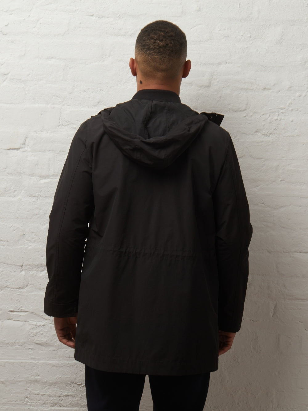 Back view of the Blake showerproof parka in Black on a model, hood down
