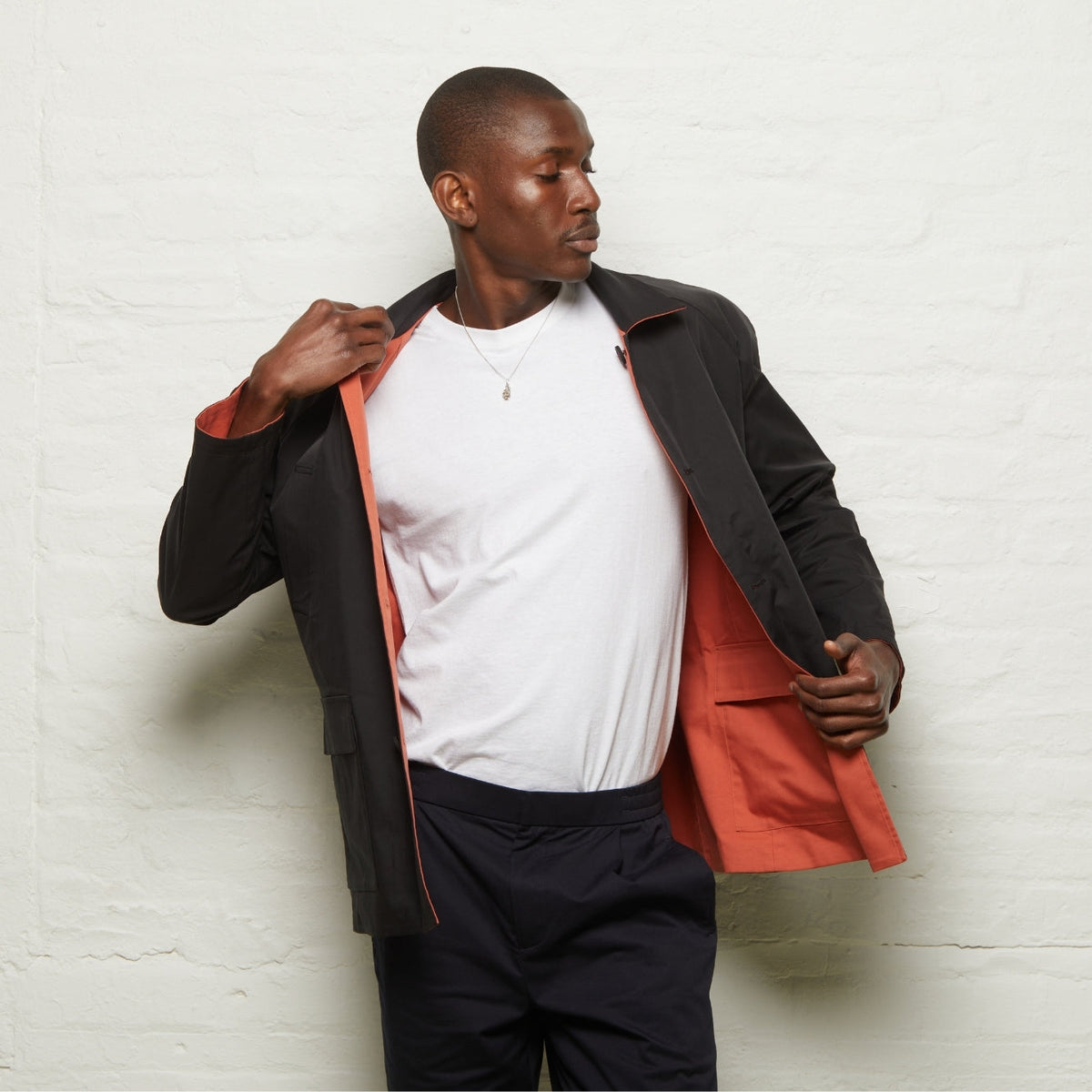 Fusilier Reversible Jacket in Orange/Black worn black side out, held open to show the orange reverse