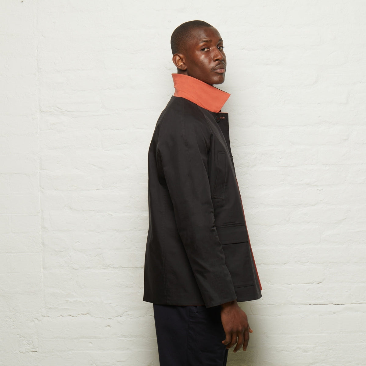 Fusilier Reversible Jacket in Orange/Black, black side out, side view with the orange collar turned up