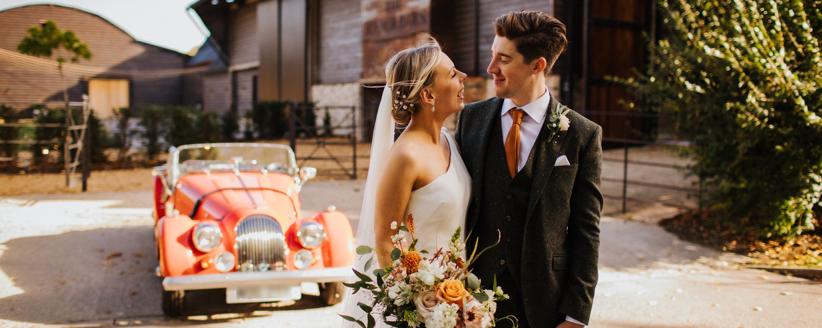 Wedding couple in front of vintage car — bespoke wedding suits at Leonard Silver